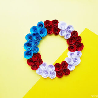 Red, white and blue wreath made with paper flowers on a yellow background