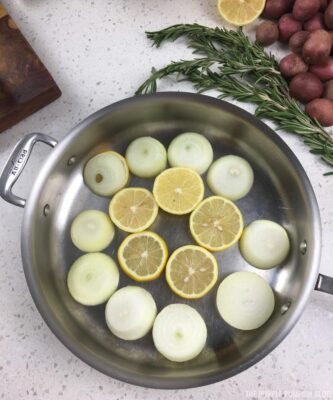 Slices of lemon and onion in bottom of roasting pan