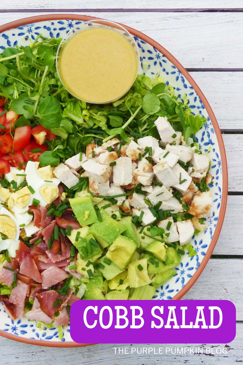 A plate filled with lettuce, watercress, chopped tomatoes, cooked chicken, chopped boiled egg, crumbled bacon, avocado, and a dish of dressing on the side. Text overlay says"Cobb Salad". Similar photos of the recipe from various angles are used throughout with different text overlays unless otherwise described.
