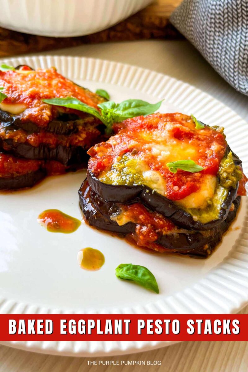 Two stacks of aubergine, mozzarella, marinara sauce and pesto, on a plate garnished with fresh basil. The text overlay says"Baked Eggplant Pesto Stacks". Similar photos of the recipe from various angles are used throughout with different text overlays unless otherwise described.