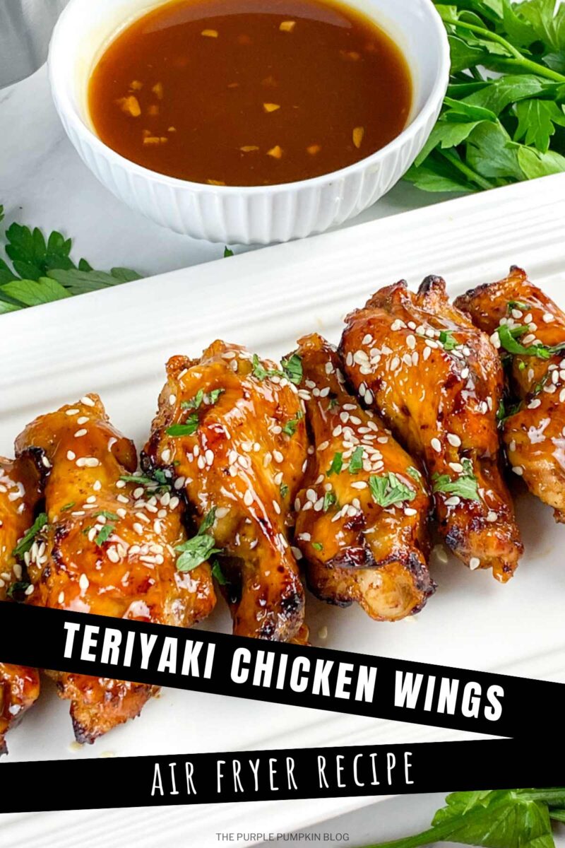A white serving plate with a line of chicken wings garnished with sesame seeds and chopped herbs. A bowl of dipping sauce is in the background. The text overlay says"Teriyaki Chicken Wings - Air Fryer Recipe". Similar photos of the recipe from various angles are used throughout with different text overlays unless otherwise described.