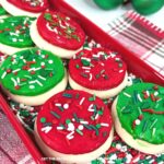 A red platter covered in red, white, and green sprinkles, and topped with homemade Lofthouse-style cookies, frosted with either red or green frosting and covered with more sprinkles.