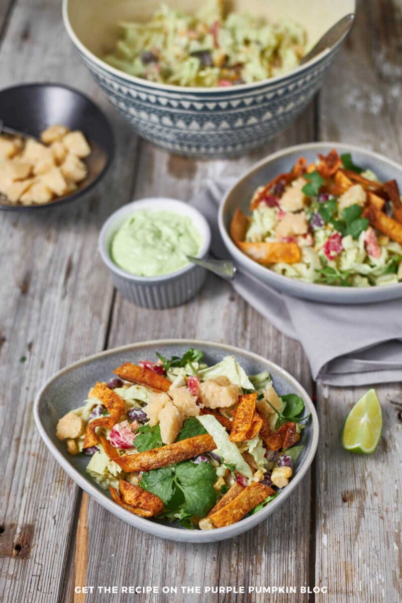 Bowl of salad - beans, corn, lettuce, bell peppers - tossed with avocado dressing and garnished with cheese and crispy tortilla strips.