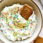 Bowl of creamy dip, topped with sprinkles with cookies and strawberries (for dipping).