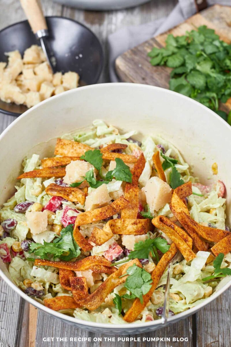Bowl of salad - beans, corn, lettuce, bell peppers - tossed with avocado dressing and garnished with cheese and crispy tortilla strips.
