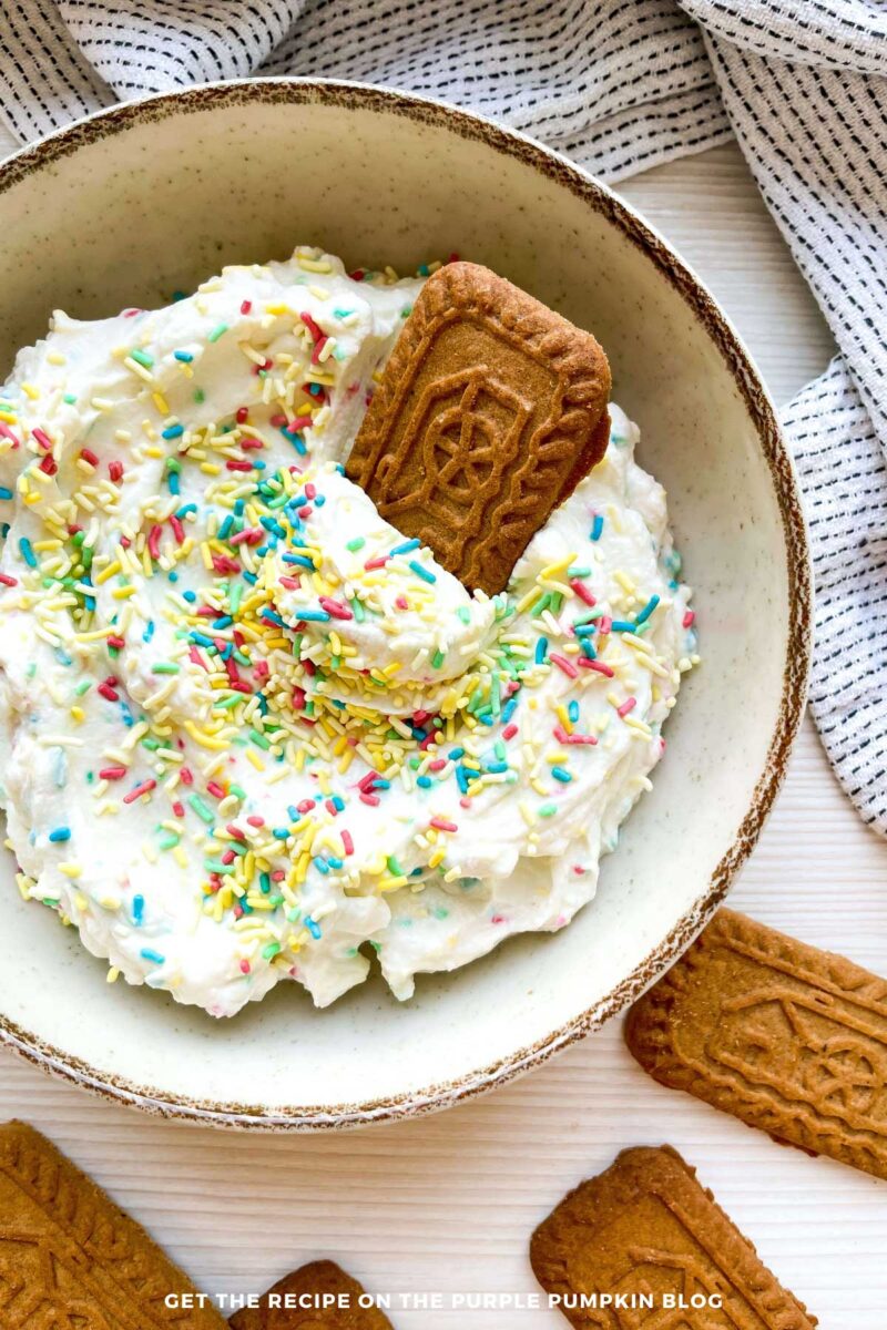 Bowl of creamy dip, topped with sprinkles with cookies and strawberries (for dipping).