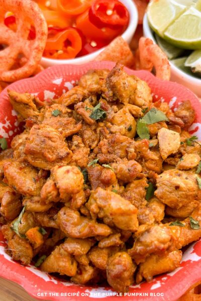 A bowl of Mexican Adobo Chicken surrounded by other taco toppings.