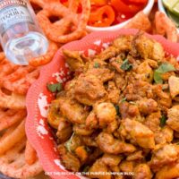 A bowl of Mexican Adobo Chicken surrounded by other taco toppings.