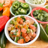 A bowl of pico de gallo surrounded by other taco toppings.