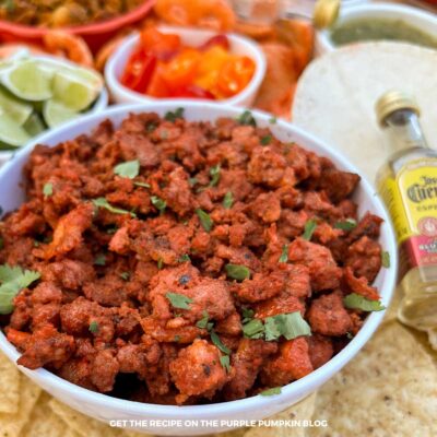 A bowl filled with tacos al pastor, garnished with chopped herbs and surrounded by taco fixins.