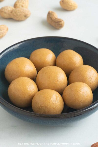 A bowl of peanut butter bites surrounded by peanuts in shells.