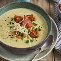 Bowl of baked potato soup garnished with croutons, cheese, and bacon.