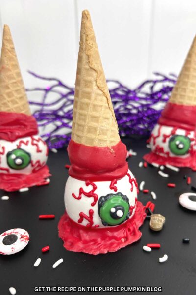 Cake balls dipped in white chocolate with green irises and bloody veins to resemble eyeballs with a waffle cone dipped in red candy sat on top.
