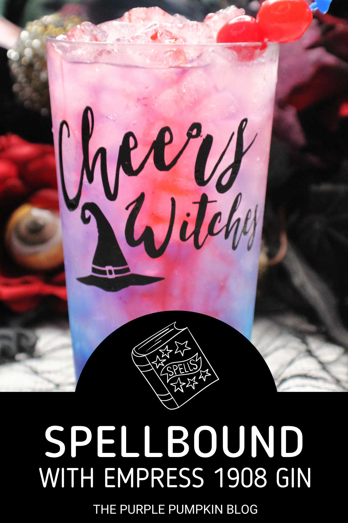 A glasses embossed with "Cheers Witches" and a witch hat, filled with a pink-purple drink and garnished with cocktail cherries. Halloween decorations are in the background. Text overlay says: Spellbound with Empress 1908 Gin
