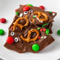 Thin pieces of chocolate covered with mini pretzels, red and green candies, candy eyes and festive sprinkles.