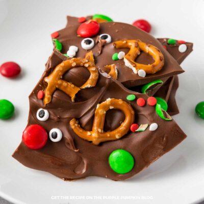 Thin pieces of chocolate covered with mini pretzels, red and green candies, candy eyes and festive sprinkles.