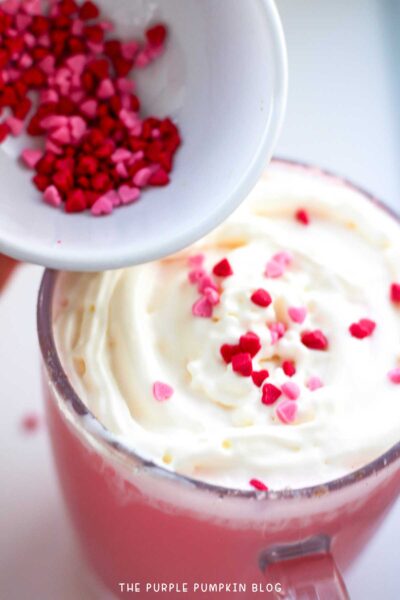 Garnishing hot chocolate with whipped cream and heart-shaped sprinkles