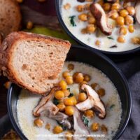 Bowls filled with mushroom spinach soup, garnished with slices of mushroom, chickpeas and toasted bread.