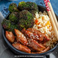 A bowl of spicy chicken with rice and broccoli, with a set of chopsticks.
