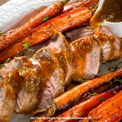 Slices of pork tenderloin on a platter with glazed carrots.