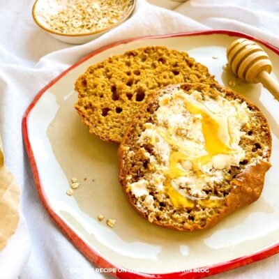 Soda bread roll, cut in half on a plate, with butter and honey spread on top.