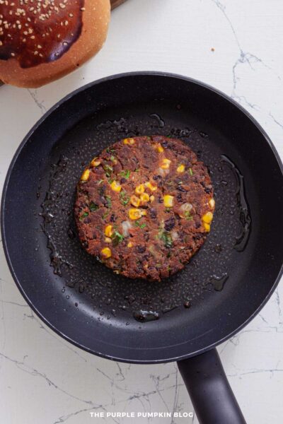 One black bean burger cooking in a non-stick skillet with oil