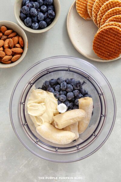Frozen blueberries, bananas, and yogurt placed in a food processor ready to be blended.
