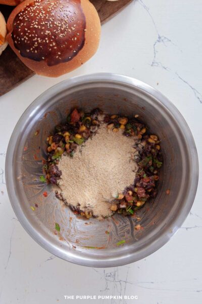 Breadcrumbs added to the black bean and vegetable mixture in a bowl