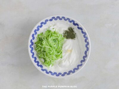 Tzatziki sauce mixture with shredded cucumber and herbs in a bowl