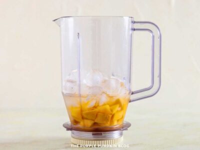 Mango chunks and ice cubes added to blender jug for mango coconut daiquiri