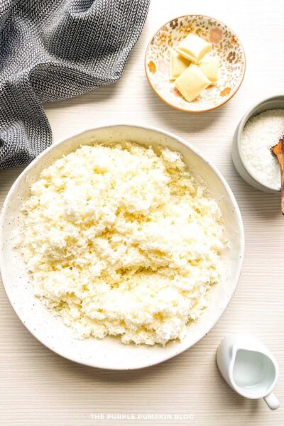 Coconut macaroon mixture fully combined in a white speckled mixing bowl, showing a fluffy and textured consistency.