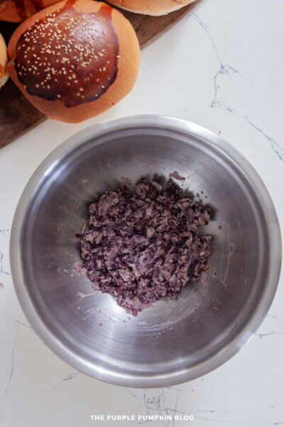 Black beans partially mashed in a stainless steel mixing bowl
