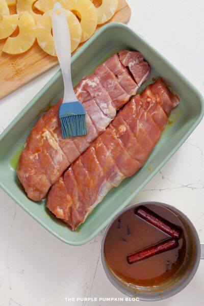 Pork tenderloin being brushed with glaze in a baking dish.