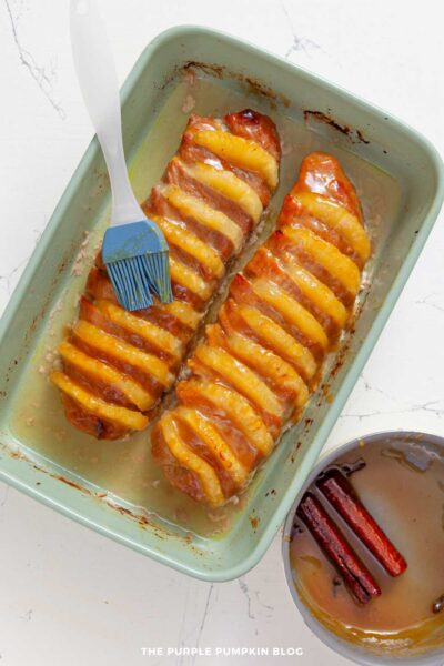 Pork tenderloin halfway through roasting being brushed with more glaze.
