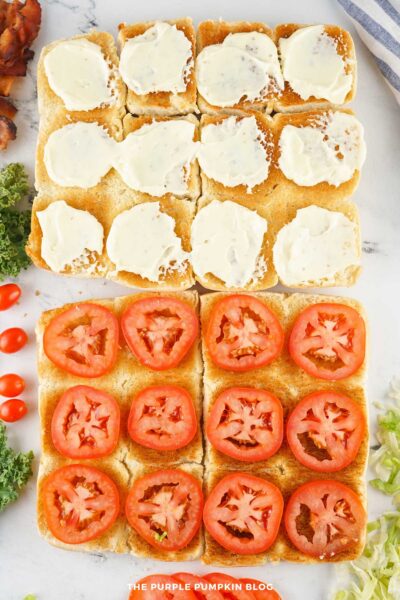 The bottom halves of the slider buns topped with evenly spaced slices of tomato, alongside the top halves with mayo.