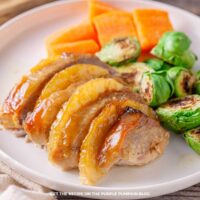 Side view of pineapple pork tenderloin with caramelized pineapple slices, roasted sprouts, and sweet potato wedges.