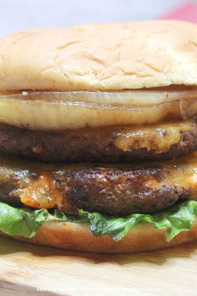 Double smash burger with cheese, lettuce, and grilled onions on a soft bun