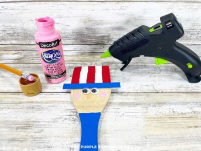 Uncle Sam wooden spoon with wiggle eyes glued on and pink cheeks dotted below using a pencil eraser.