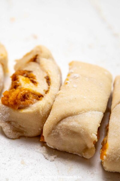 Close-up image of pumpkin pie fingers with flaky crust, showcasing autumn-inspired flavors and pumpkin filling inside.