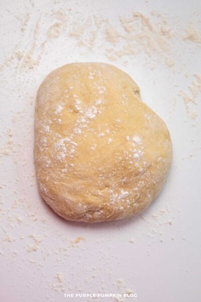 Flour-dusted bread dough for baking on a white surface.