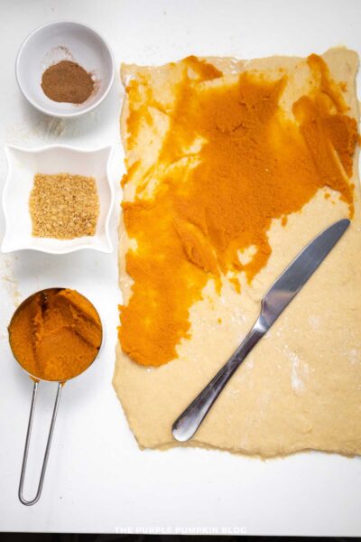 Cream cheese pumpkin filling with ground ginger, brown sugar, and pumpkin puree on a white surface.