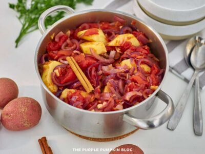 Cinnamon stick added on top of beef, potatoes, and tomato mixture in a pot for seasoning.