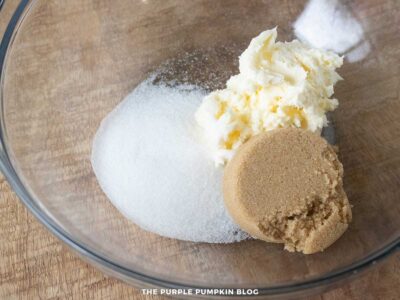 Clear mixing bowl with softened butter, granulated sugar, and brown sugar before being creamed together.