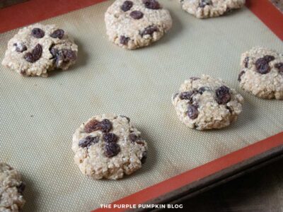 Unbaked oatmeal raisin cookie dough pressed flat on a silicone baking mat, ready for baking.