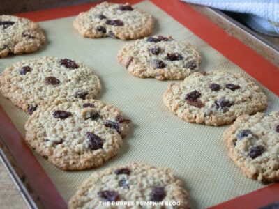 Golden brown oatmeal raisin cookies just out of the oven on a silicone baking mat.