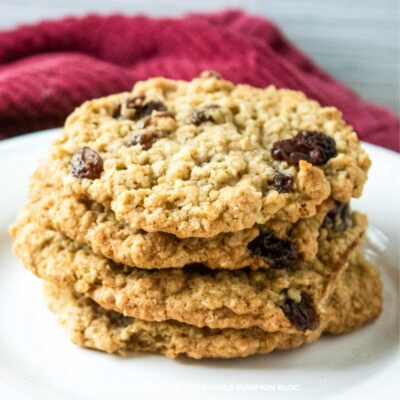Stack of pumpkin spice oatmeal raisin cookies on a white plate with a red fabric background.