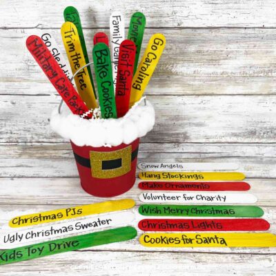 Colorful Christmas to-do list sticks in Santa-themed bucket with snow.