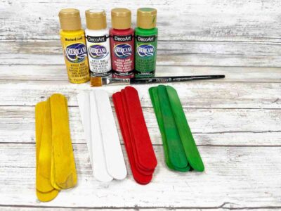 Bright acrylic paint bottles and popsicle sticks for arts and crafts projects.