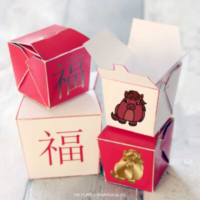 Stack of assembled red and cream Chinese New Year take out boxes made from a free printable paper template, featuring traditional Chinese characters.