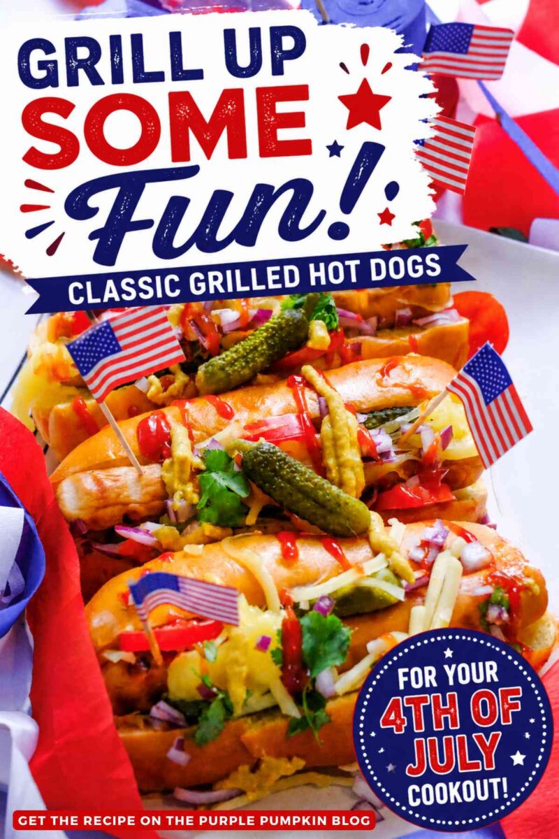 Close-up of grilled hot dogs topped with cheese, pickles, diced red onion, ketchup, mustard, and cilantro, decorated with small American flags and surrounded by red, white, and blue party decorations. Text overlay says: "Grill Up Some Fun! Classic Grilled Hot Dogs For Your 4th Of July Cookout!"